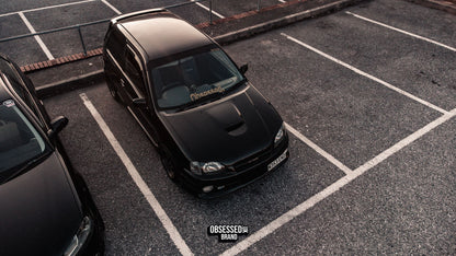 Black Renault Clio in a car park with a gold Obsessed heart windscreen banner