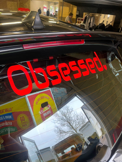 Red Obsessed heart sticker fitted to the rear window of a black car