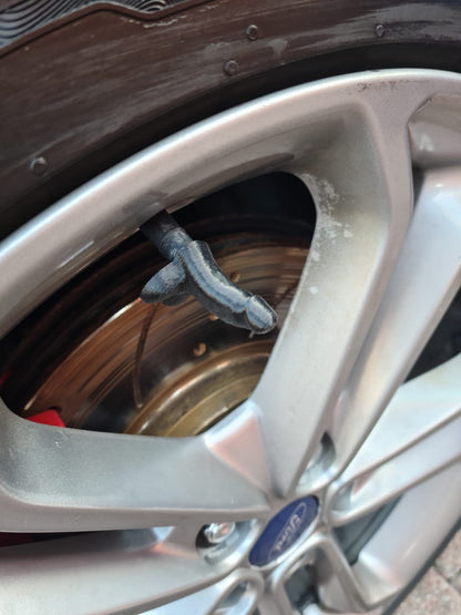 Grey novelty tyre valve cap fitted to a Ford alloy wheel